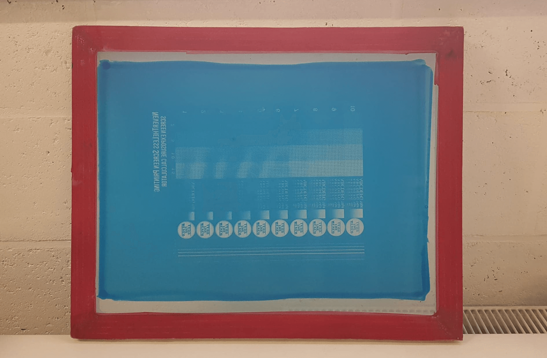 An exposed and revealed screen printing frame with an exposure calculator stencil