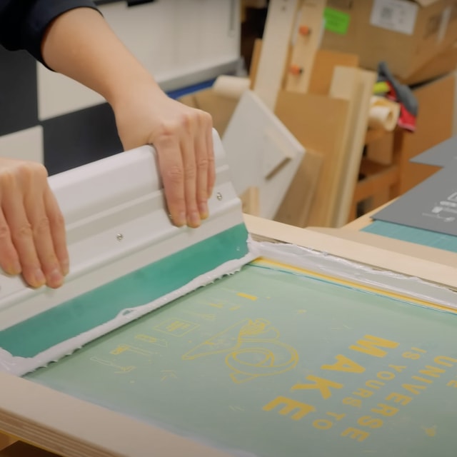 focus on hands printing white ink on black posters